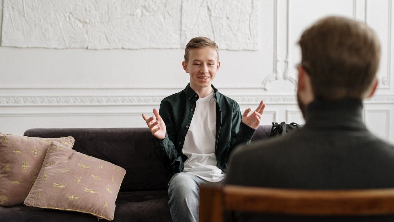 Sell Business A man engaging in a lucrative business conversation with a young boy in a living room. Exit Advisor Business Broker