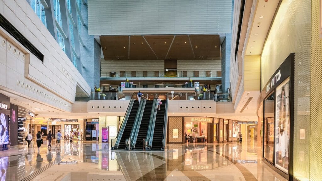 Sell Business The interior of a shopping mall, bustling with business and filled with escalators. Exit Advisor Business Broker