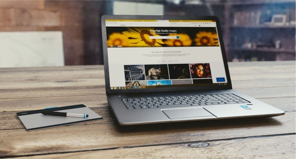 Sell Business A laptop is placed on top of a wooden table in a content website office. Exit Advisor Business Broker
