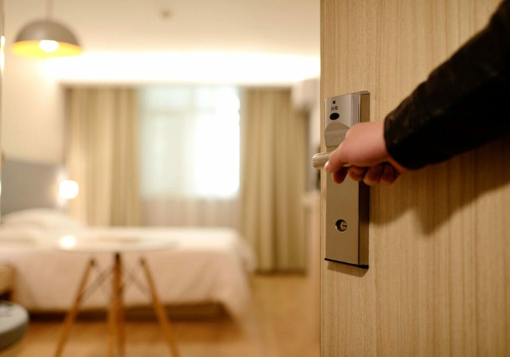 How to Sell a Hotel Business: A Guide to a Premium Exit. Sell Business A person in the hotel business demonstrating a premium exit by holding a door handle in a hotel room. Exit Advisor Business Broker