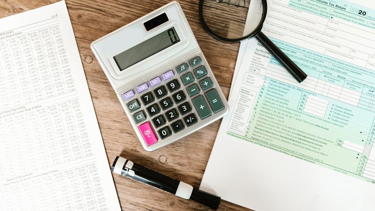 Sell Business A magnifying glass, calculator and tax forms on a wooden table in a life insurance business setting. Exit Advisor Business Broker