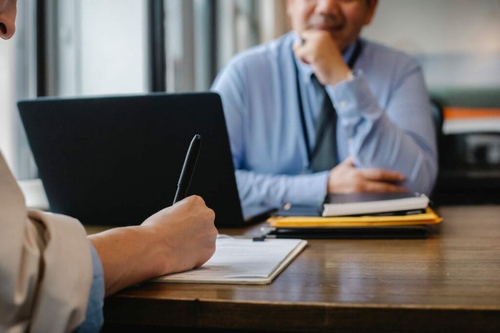 How to Sell a Government Contract Business? Expert Guide For Exit.
Sell Business Two people engaging in a conversation at a desk about government contract business. Exit Advisor Business Broker