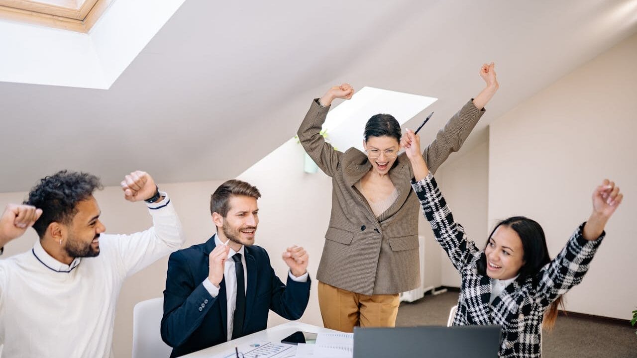 Sell Business A group of business people **celebrating** in an office. Exit Advisor Business Broker