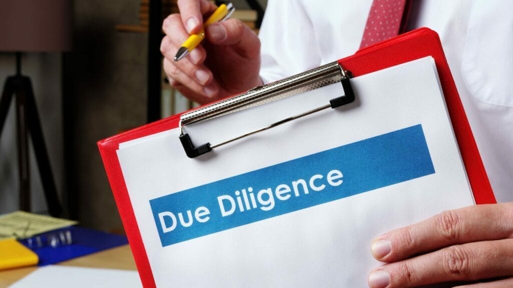 Sell Business A person holding a clipboard with the words "due diligence" written on it, essential for buying a business. Exit Advisor Business Broker - How to Due Diligence When Buying or Selling a Business