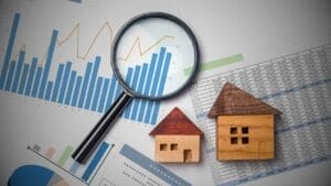 Mexico’s Real Estate Investment Trusts (REITs) for Foreign Investors - Sell Business Magnifying glass on financial graphs with wooden house models, symbolizing real estate market analysis in Mexico. Exit Advisor Business Broker