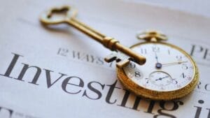 How to Buy a Business with Your EB5 Visa: A Step-by-Step Guide - Sell Business A vintage key resting on a newspaper with the word "investing" visible, overlaid by a classic pocket watch showing the time. Exit Advisor Business Broker