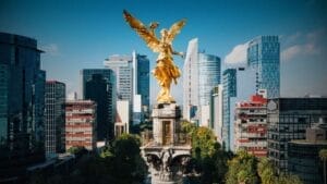 Understanding Mexico's Fideicomiso System for Foreign Buyers - Sell Business The angel of independence statue in Mexico City, a golden angel atop a column, with Mexico REITs skyscrapers in the background under a clear blue sky. Exit Advisor Business Broker