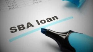 Selling Your Business with an SBA Loan- Sell Business A highlighter emphasizing the words "SBA loan" on a financial document related to a business sale with numerical data. Exit Advisor Business Broker